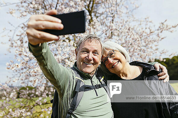 Liebevolles älteres Paar  das an einem sonnigen Tag ein Selfie mit dem Smartphone macht