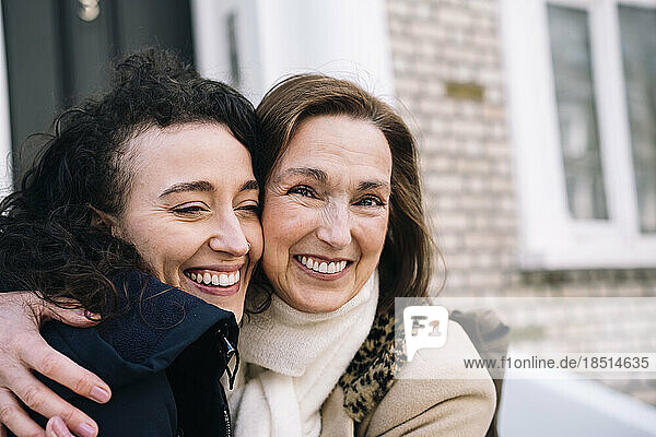 Happy aunt embracing niece outside building