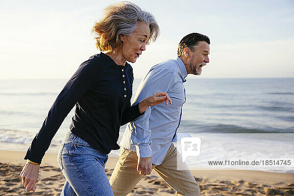 Active man and woman running at beach