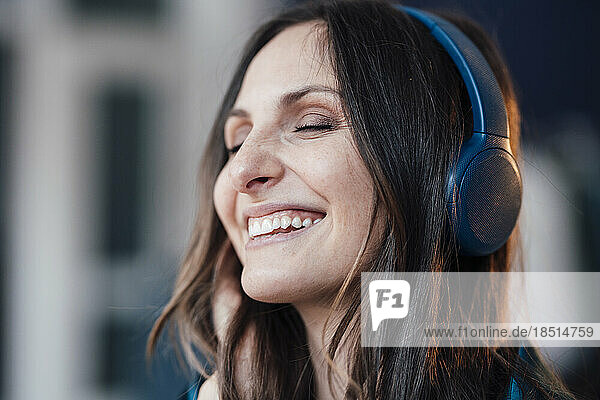 Happy woman wearing wireless headphones listening to music