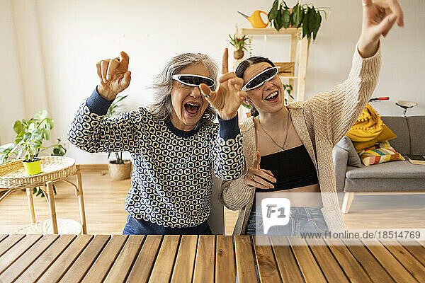 Fröhliche Mutter und Tochter mit intelligenten Brillen haben zu Hause Spaß