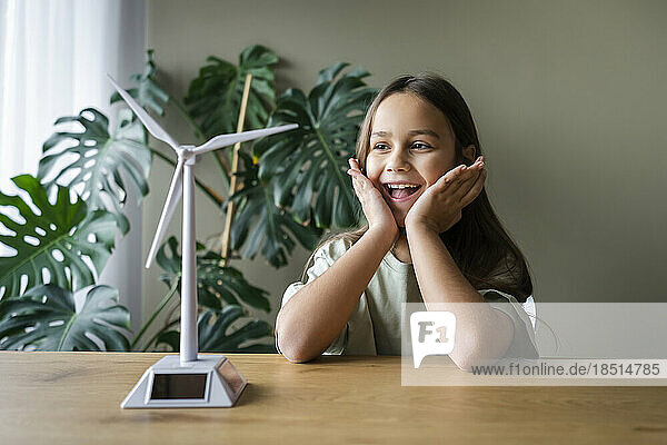 Surprise girl looking at wind turbine model on table