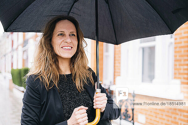 Happy woman holding black umbrella