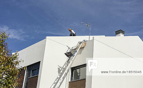 Engineer working on roof of house under sky