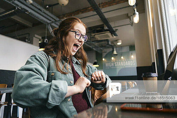 Successful young freelancer screaming at cafe