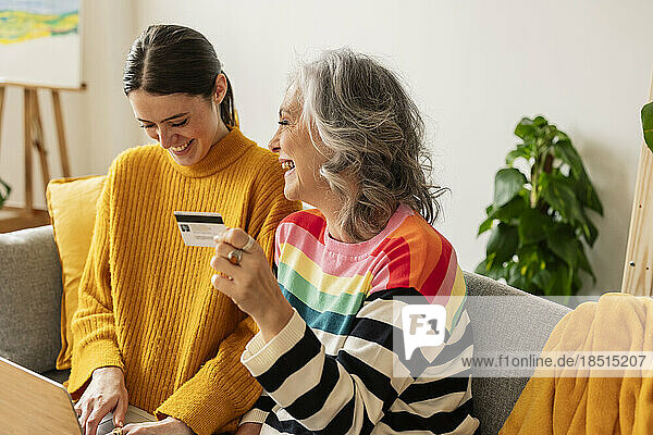 Glückliche Tochter und Mutter  die zu Hause online mit Kreditkarte einkaufen
