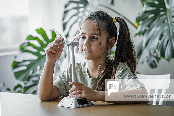 Girl rotating wind turbine model at home