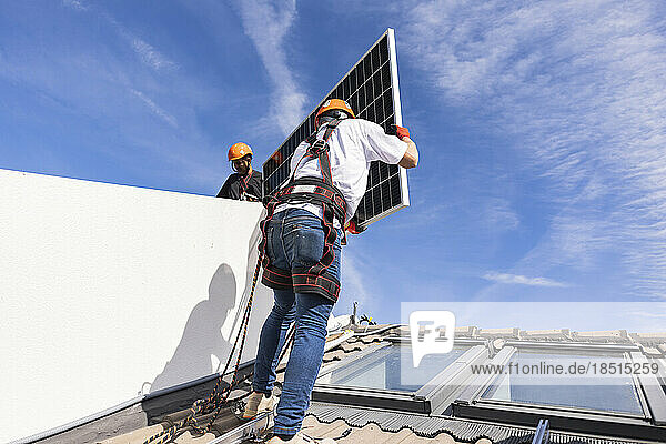 Engineers installing solar panel under sky