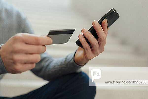 Hände eines Geschäftsmannes mit Kreditkarte und Smartphone