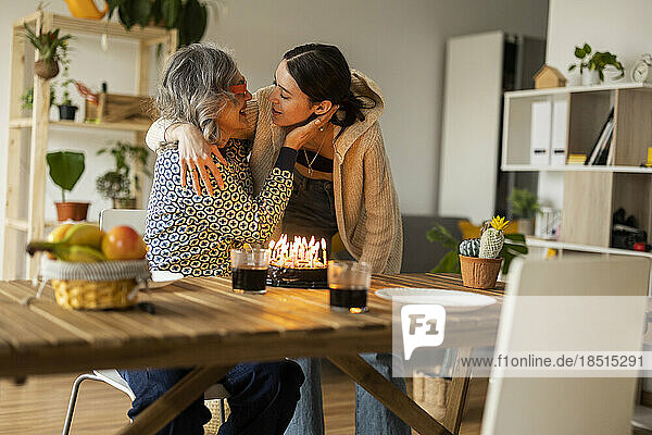 Happy mother embracing daughter and celebrating birthday at home