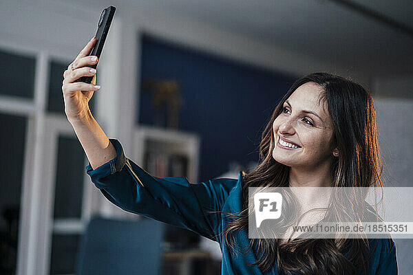 Glückliche junge Frau  die zu Hause ein Selfie macht