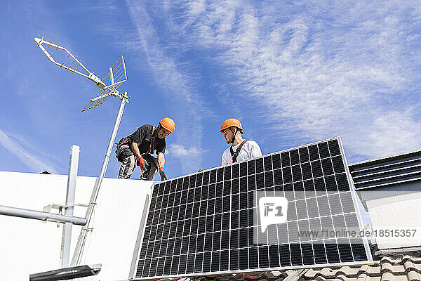 Engineers installing solar panel on sunny day