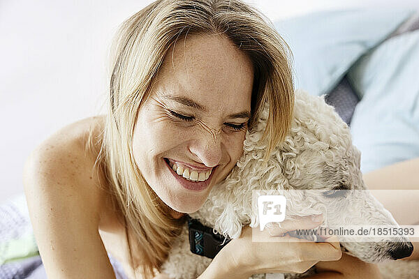 Happy woman embracing dog at home