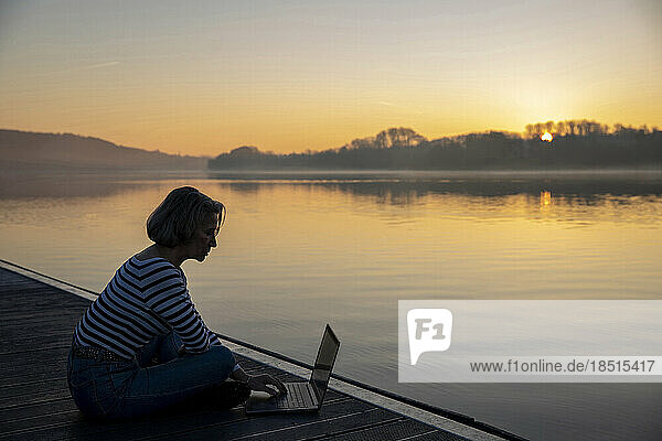 Freelancer working by lake in morning