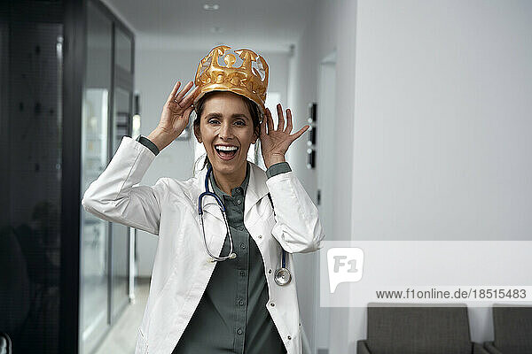 Happy doctor wearing crown standing in clinic