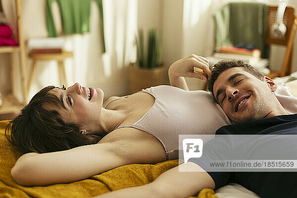 Smiling boyfriend with woman relaxing on bed at home