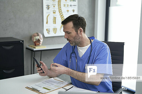 Doctor talking on video call through smart phone in clinic