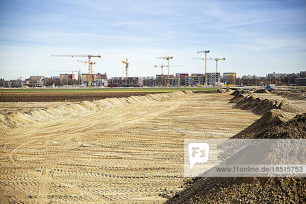 Germany  Bavaria  Munich  Sandy area prepared for construction site with industrial cranes in background