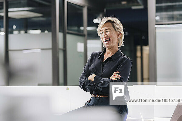Playful businesswoman winking in office