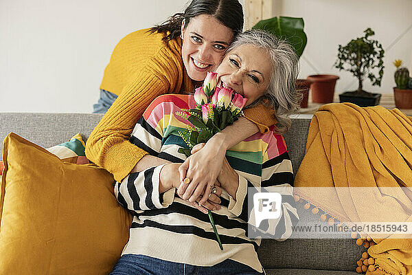 Happy daughter with mother holding flowers at home