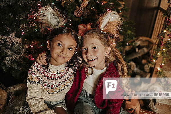Nachdenklich lächelnde Schwestern sitzen zu Weihnachten zusammen