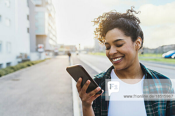 Happy young woman using smart phone on road
