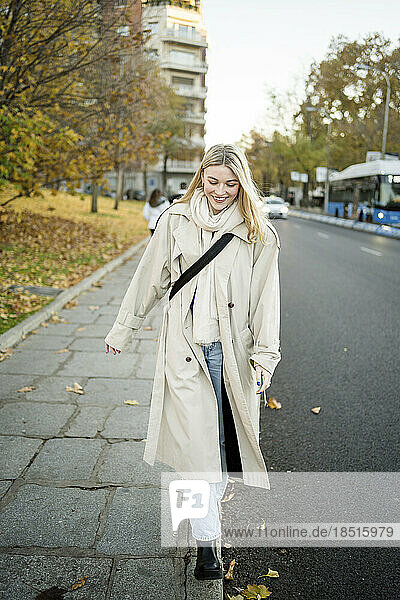Smiling young woman strolling on sidewalk