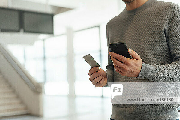 Mann hält Kreditkarte und Smartphone in der Hand