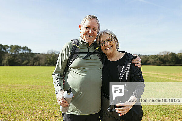 Lächelnder älterer Mann mit Arm um Frau  die auf grüner Landschaft steht