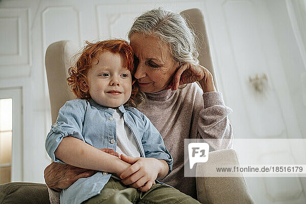 Großmutter und Enkel sitzen zu Hause im Sessel
