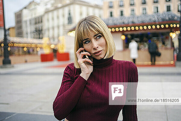 Thoughtful blond woman talking on smart phone