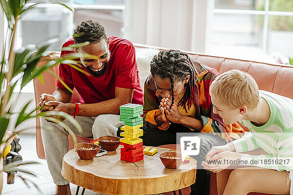 Young multiracial friends playing block removal game in living room