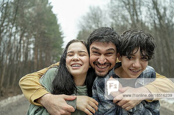 Glücklicher Vater umarmt Sohn und Tochter im Teenageralter