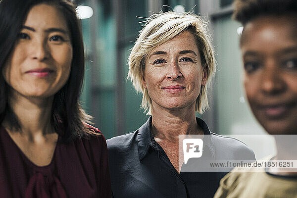 Smiling businesswoman standing with colleagues in office