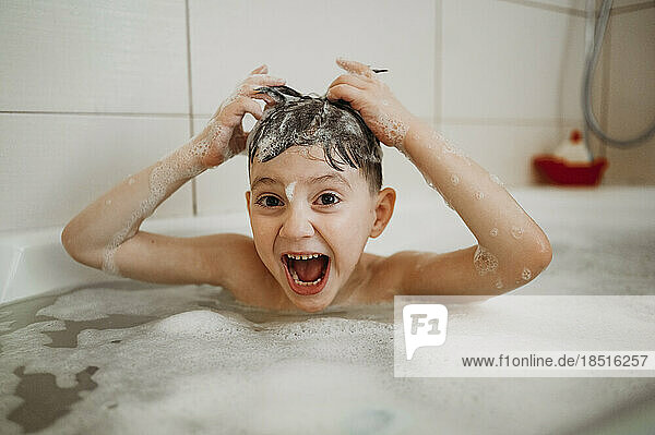 Glücklicher Junge  der zu Hause Spaß in der Badewanne hat