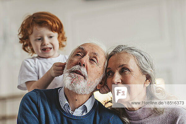 Playful boy with grandparents spending leisure time at home