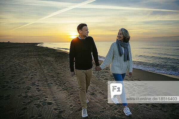 Lächelndes älteres Paar  das am Strand spaziert