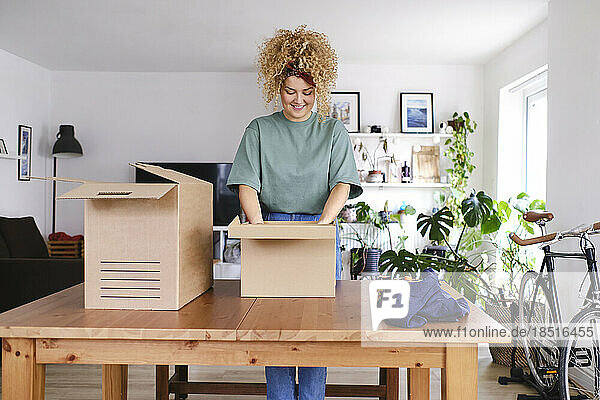 Smiling young woman packing orders at desk