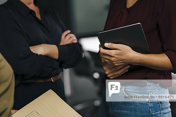 Businesswoman holding tablet PC with colleagues in office