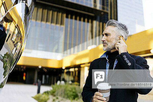 Businessman talking on smart phone in front of building