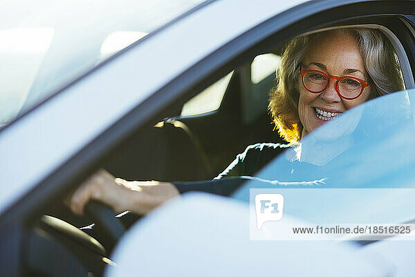 Happy mature woman driving car