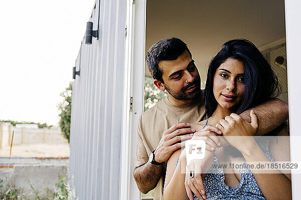 Man with arm around woman near doorway of container home