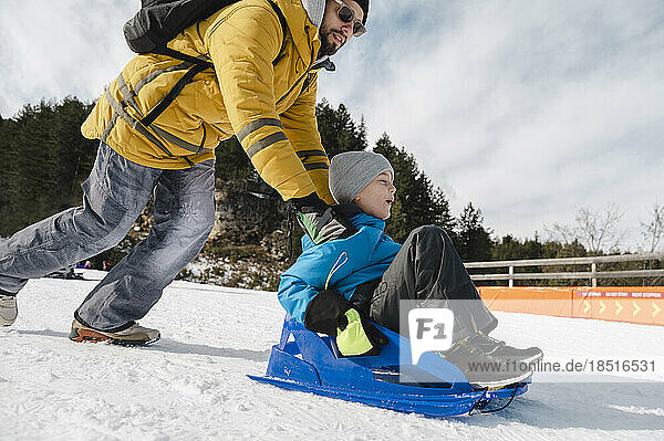 Father with son tobogganing on snow