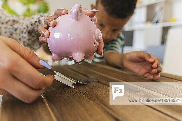 Mother opening piggy bank to count coins at home