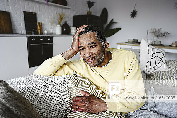 Thoughtful man with head in hand sitting on sofa at home