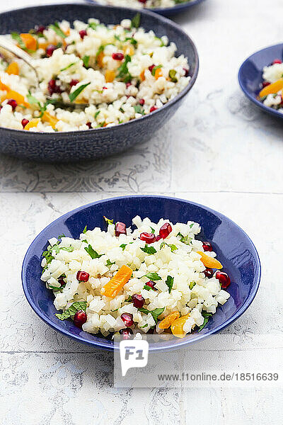 Bowls of cauliflower salad with pomegranate seeds  pistachios  mint  parsley and dried apricot