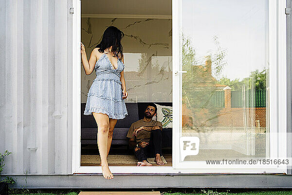 Frau steht in der Nähe der Tür und schaut ihren Freund an  der im Containerhaus sitzt