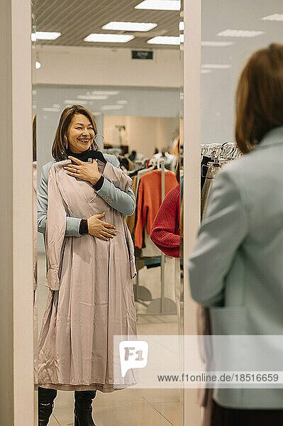 Happy woman with dress looking in mirror