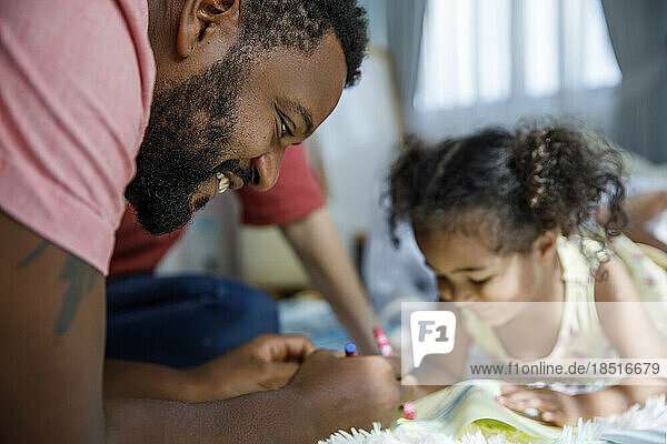 Glücklicher Mann macht mit seiner Tochter zu Hause eine Skizze