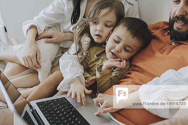 Glückliche Familie  die gemeinsam zu Hause Laptop benutzt